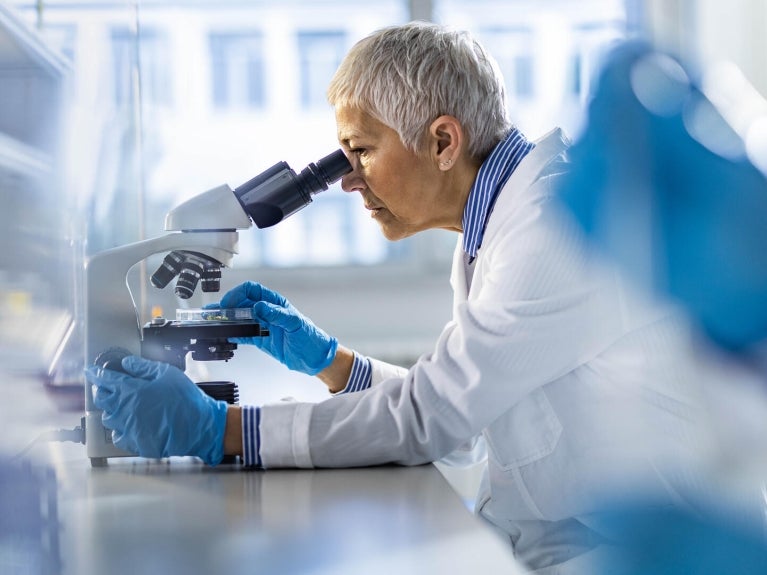 Healthcare worker looking through a microscope.